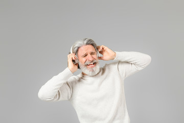 Poster - Cool senior man listening to music on grey background