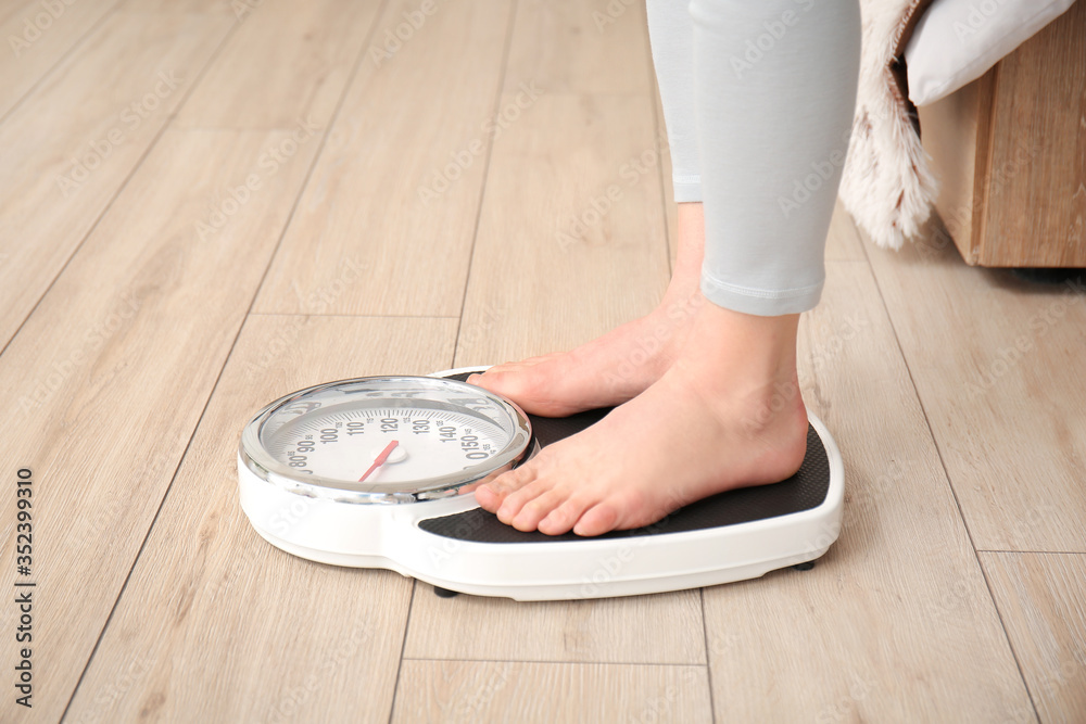 Young woman measuring her weight at home