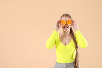 Wall Mural - Young woman with orange on color background. Diet concept