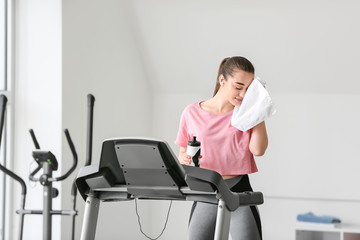 Sticker - Sporty young woman resting after training on treadmill in gym