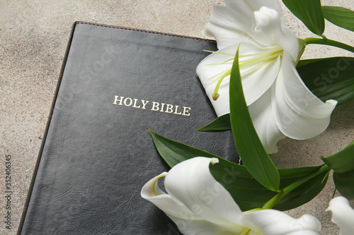 Holy Bible and flowers on grey background, closeup