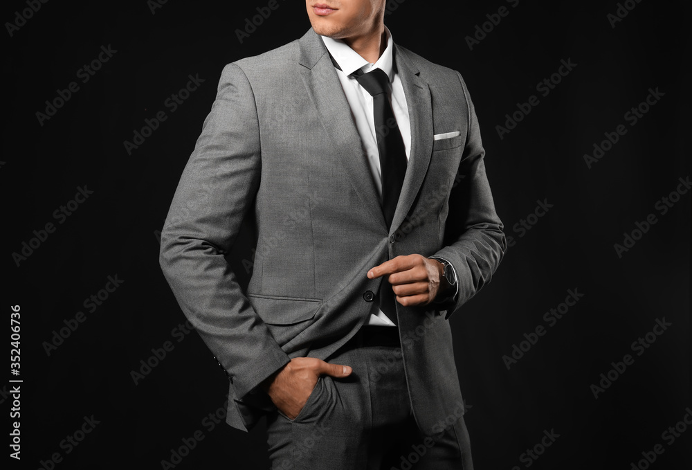 Handsome young man in elegant suit on dark background