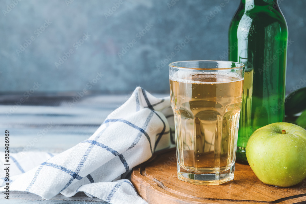 Bottle and glass of apple cider on table