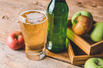 Bottle and glass of apple cider on table