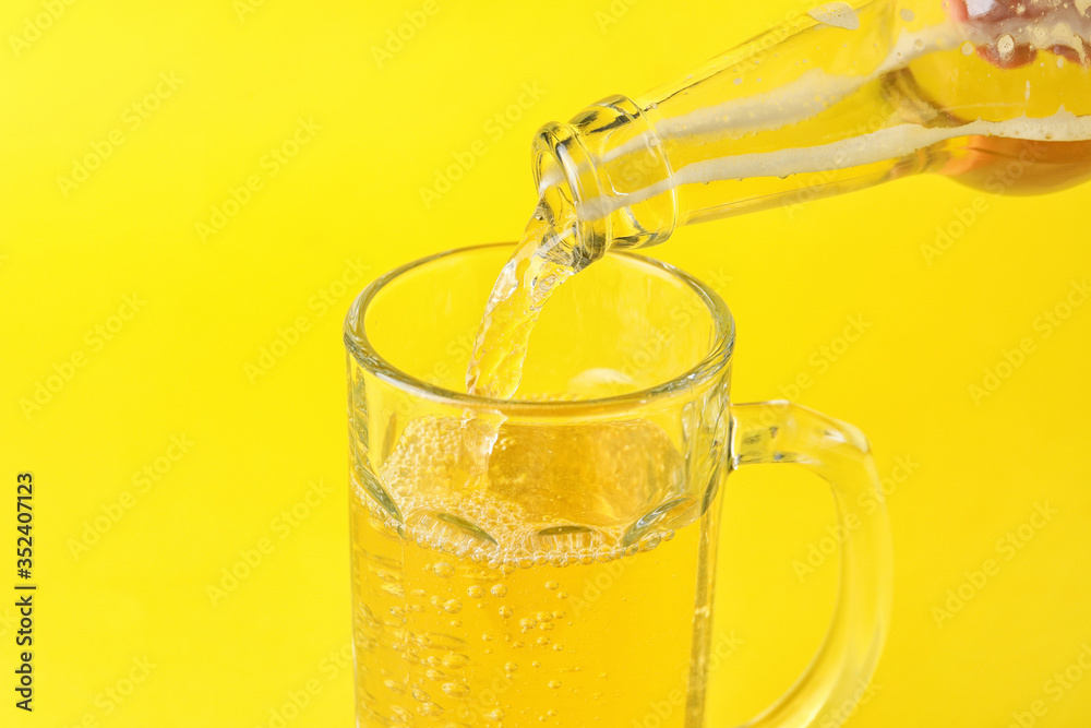 Pouring of apple cider in mug on color background