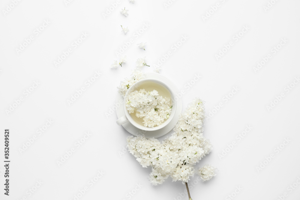 Composition with beautiful lilac flowers and cup on white background
