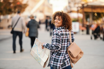 Rear view of attractive mixed race female tourist visiting new town.