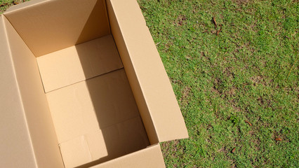 An empty cardboard box on top of green lawn. View from above.