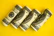 © anna.stasiia - American dollars in rolls. Saving money concept on yellow background with copy space for text