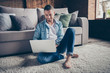 Photo of handsome homey guy relaxing sitting comfy fluffy carpet near couch browsing notebook freelancer remote work stay home good mood quarantine time weekend living room indoors