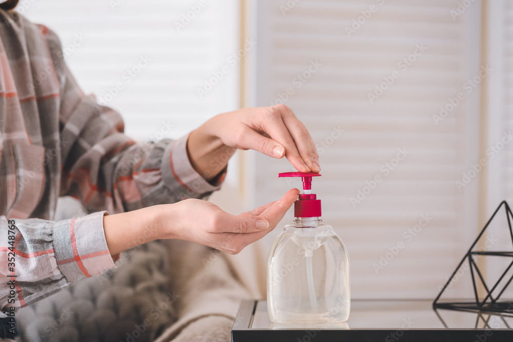 Woman applying disinfectant on her hands at home