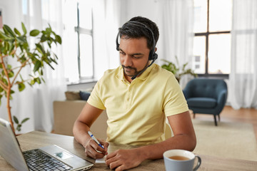 Wall Mural - remote job, technology and people concept - indian man with headset and laptop computer having video conference at home office