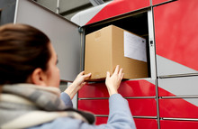 Mail Delivery And Post Service Concept - Woman Putting Box To Automated Parcel Machine
