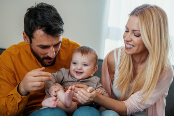 Wall Mural - Loving parents with their cute baby playing on bed.