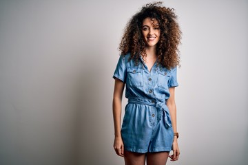 Young beautiful woman with curly hair and piercing wearing casual denim dress with a happy and cool smile on face. Lucky person.