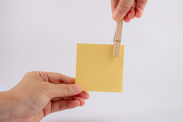 hand holding Yellow sticky notes with wood clothespin, isolated on white background