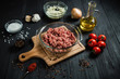 Raw minced meat with ingredients on a black wooden table