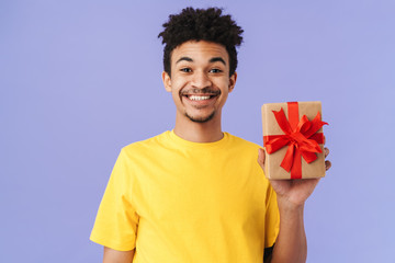 Wall Mural - Photo of happy african american man holding gift box and smiling