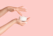 canvas print picture - Unrecognizable girl applying cream from jar onto her hands against pink background, blank space