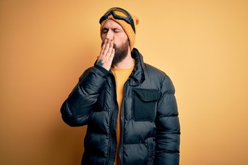 Poster - Handsome skier bald man with beard skiing wearing snow sportswear and ski goggles bored yawning tired covering mouth with hand. Restless and sleepiness.