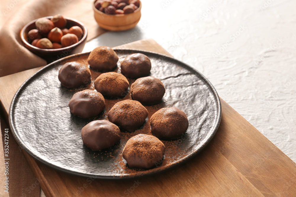 Plate with tasty chocolate candies on white background