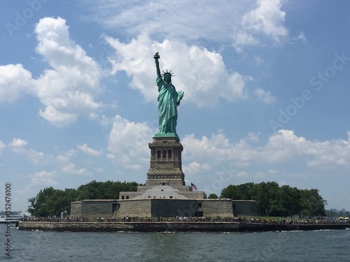 Fotografía Statue Of Liberty By River Against Cloudy Sky