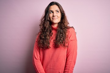 Poster - Young beautiful woman with curly hair wearing turtleneck sweater over pink background smiling looking to the side and staring away thinking.