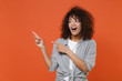 © ViDi Studio - Funny young african american woman girl in gray casual clothes isolated on orange background studio portrait. People emotions lifestyle concept. Mock up copy space. Pointing index fingers aside up.