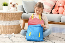 Cute Little Girl Packing Schoolbag At Home