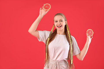 Wall Mural - Young woman with grapefruit and measuring tape on color background. Diet concept