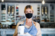 © Halfpoint - Woman owner with face mask in coffee shop, lockdown and back to normal concept.