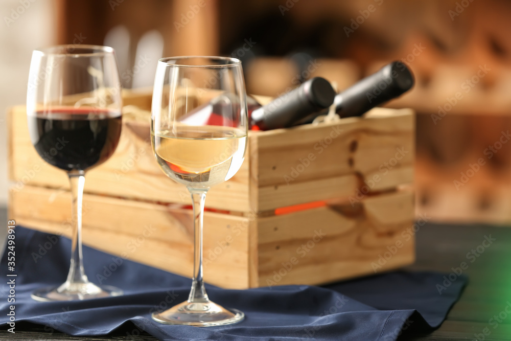 Box with bottles of wine and glasses in cellar