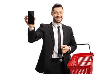 Wall Mural - Businessman with a shopping basket smiling and showing a mobile phone