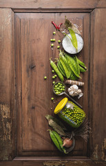 Wall Mural - Vegetarian concept. Fresh garden peas canning in pods in glass jar with seasonings on a rustic wooden table, top view. Vegetables harvest preserving. Food background