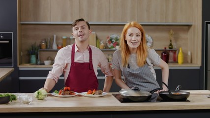 Wall Mural - Cooking show hosts chefs, male and female, showing cooked dish into camera. Morning TV cooking programme