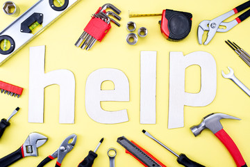 Wall Mural - Coplet of repair tools on a yellow background and the word HELP made of wooden letters. Equipment for construction. Repair tool kit. View from above