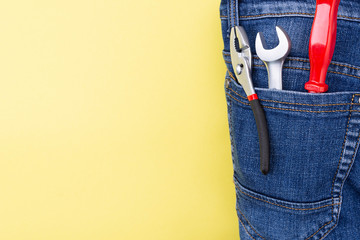 Wall Mural - tools in the pocket of a craftsman jeans on a yellow background with place for text