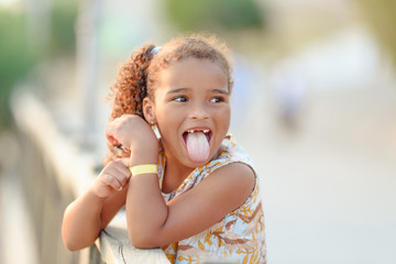 Very funny cute little girl showing tongue, with pigtails, summer, outdoors, concept childhood