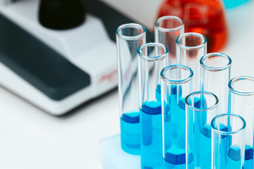 Scientific laboratory with microscope and test tubes with samples, close up photo