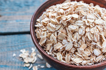 Wall Mural - Bowl with raw oatmeal on a background of blue boards.