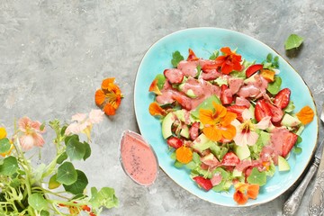 Sticker - salad with nasturtium flowers and leaves with strawberries and avocados. dressed with strawberry vinaigrette or strawberry dressing with poppy seeds. edible flowers. top view, copy space