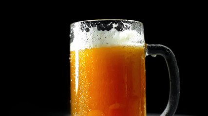 Wall Mural - mug of fresh, cold light beer with foam isolated on black