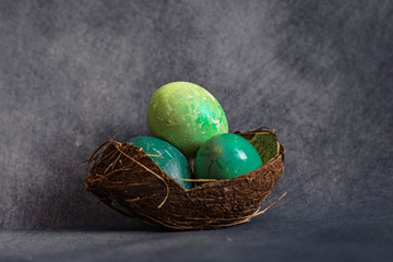 Easter eggs in a coconut shell on a gray background with coffee beans around