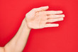© Krakenimages.com - Hand of caucasian young man showing fingers over isolated red background stretching and reaching with open hand for handshake, showing palm