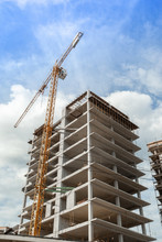 Multi-storey Residential Building Under Construction And Crane On A Background Of Blue Sky