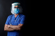 Medico  con protezioni mascherina chirurgica , visiera in plastica e camice blu isolato su sfondo nero