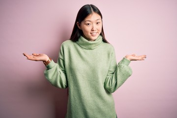 Sticker - Young beautiful asian woman wearing green winter sweater over pink solated background smiling showing both hands open palms, presenting and advertising comparison and balance