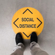 A Person Standing On A Social Distancing Sign