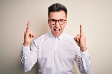 Wall Mural - Young handsome business mas wearing glasses and elegant shirt over isolated background shouting with crazy expression doing rock symbol with hands up. Music star. Heavy concept.