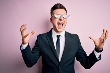 Wall Mural - Young handsome caucasian business man wearing funny thug life glasses crazy and mad shouting and yelling with aggressive expression and arms raised. Frustration concept.